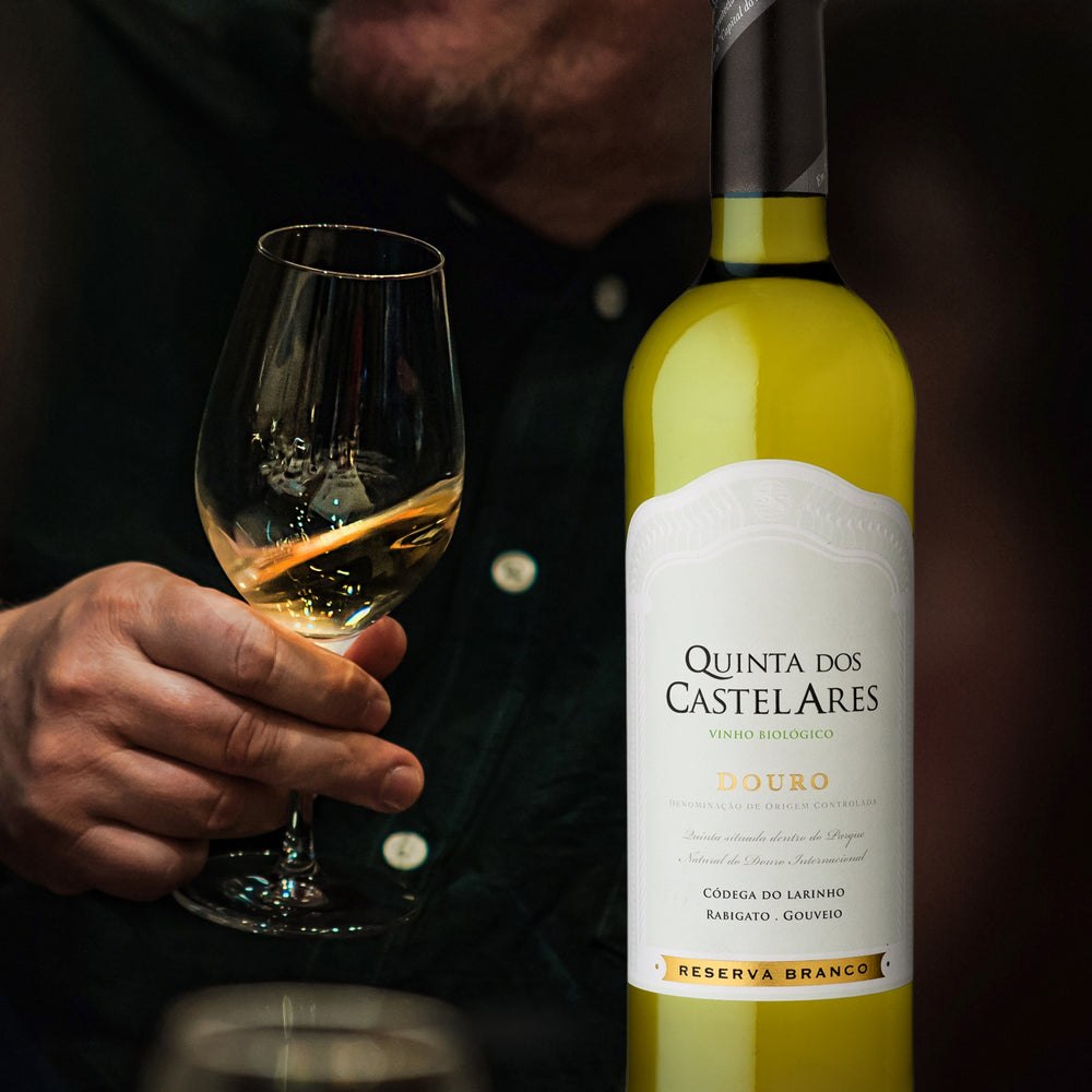 Quinta dos Castelares,  Reserva Weißwein / Biowein aus dem Douro / Portugal.  Eine Männerhand hält ein gefülltes Weinglas neben der Flasche.