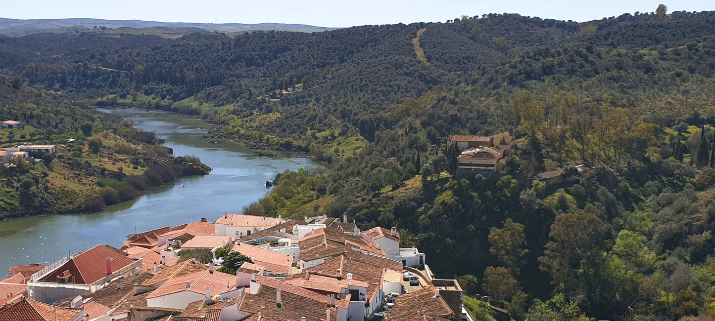 Panoramablick auf das Guadiana-Tal mit Flusslauf, bewaldeten Hügeln und einem Dorf mit roten Ziegeldächern am Hang im Alentejo, Portugal.
