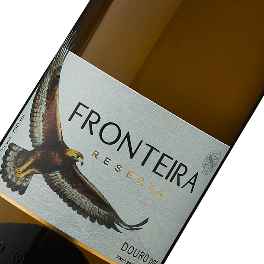 
                  
                    Flasche Fronteira Reserva Weißwein aus dem Douro-Gebiet, Portugal. Der Wein ist dunkelgelb/bernsteinfarben und die Flasche ist bauchiger als das Standardmodell. Das Etikett ist weiß und zeigt einen goldbraunen Adler, der auf die Seitenkante blickt, darüber der Schriftzug „FRONTEIRA RESERVA“ und darunter „DOURO DOC“. Die Flasche hat einen goldenen Schraubverschluss.
                  
                