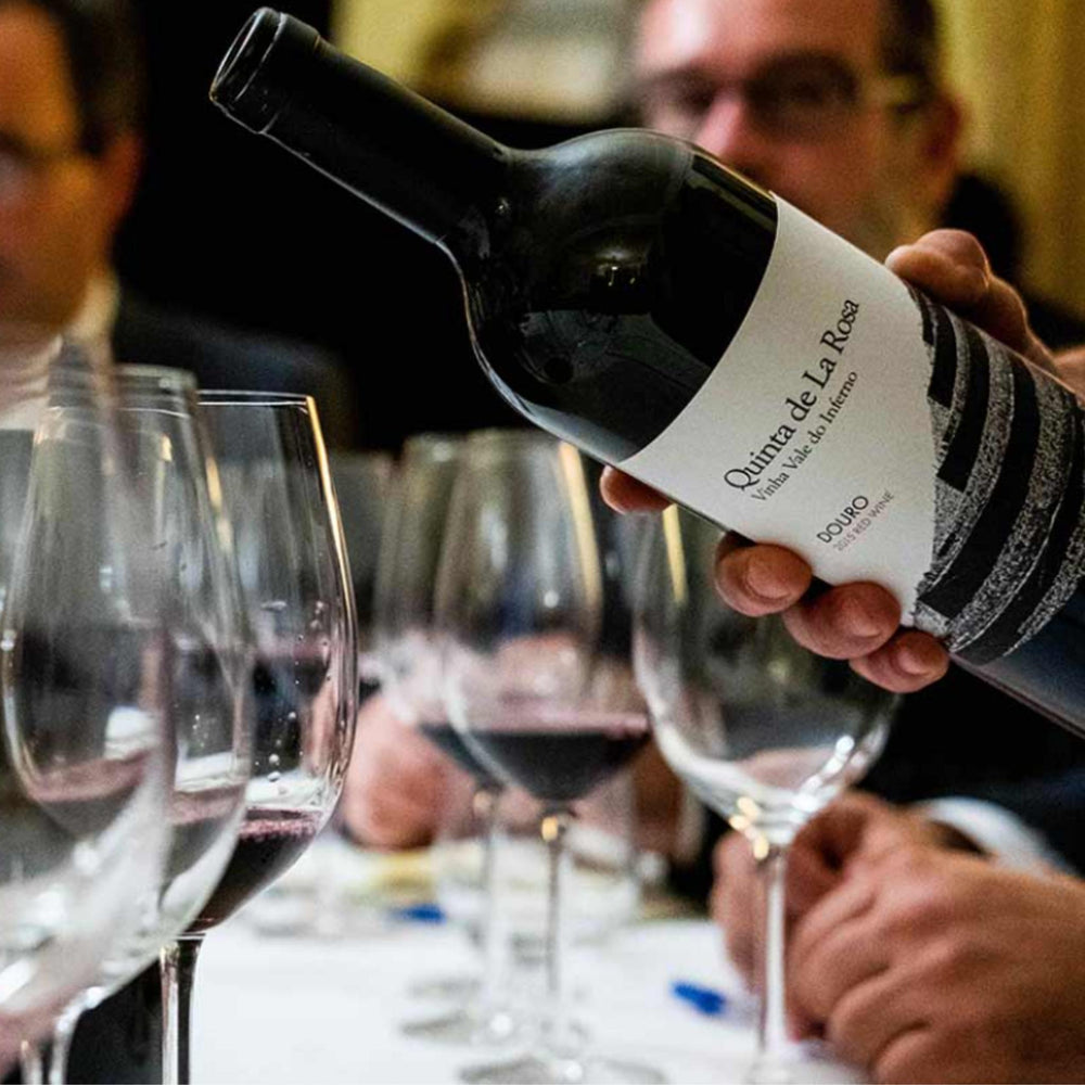 
                  
                    Vinha Vale do Inferno, ein Rotwein vom Weingut Quinta de la Rosa aus dem Douro/Portugal. Bild mit Weingläsern und Menschen im Hintergrund.
                  
                