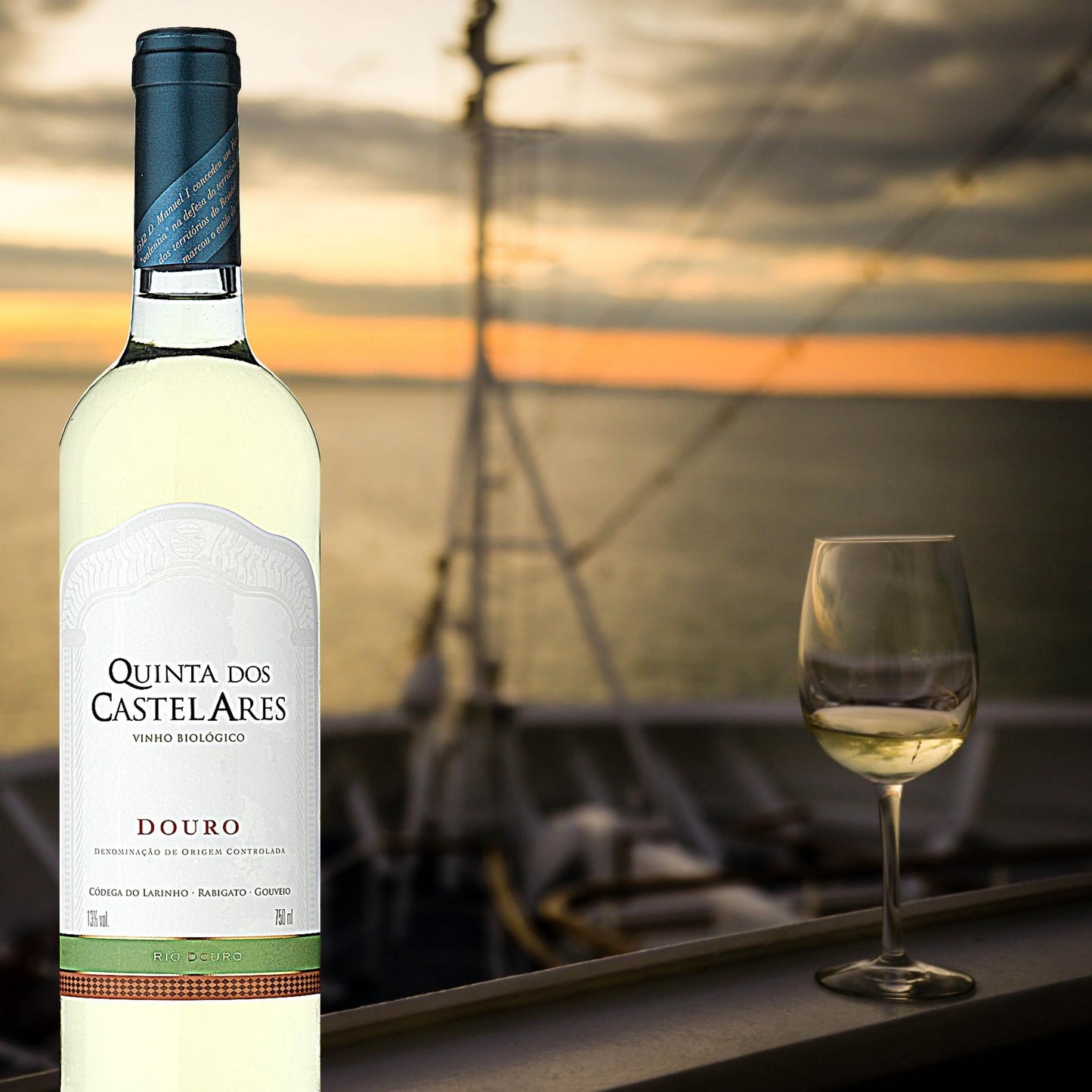 
                  
                    Quinta dos Castelares Colheita Weißwein aus dem Douro / Portugal. Biowein. Im Hintergrund ist das Meer zu sehen. Bild mit einem Segelschiff und einem Weißweinglas.
                  
                