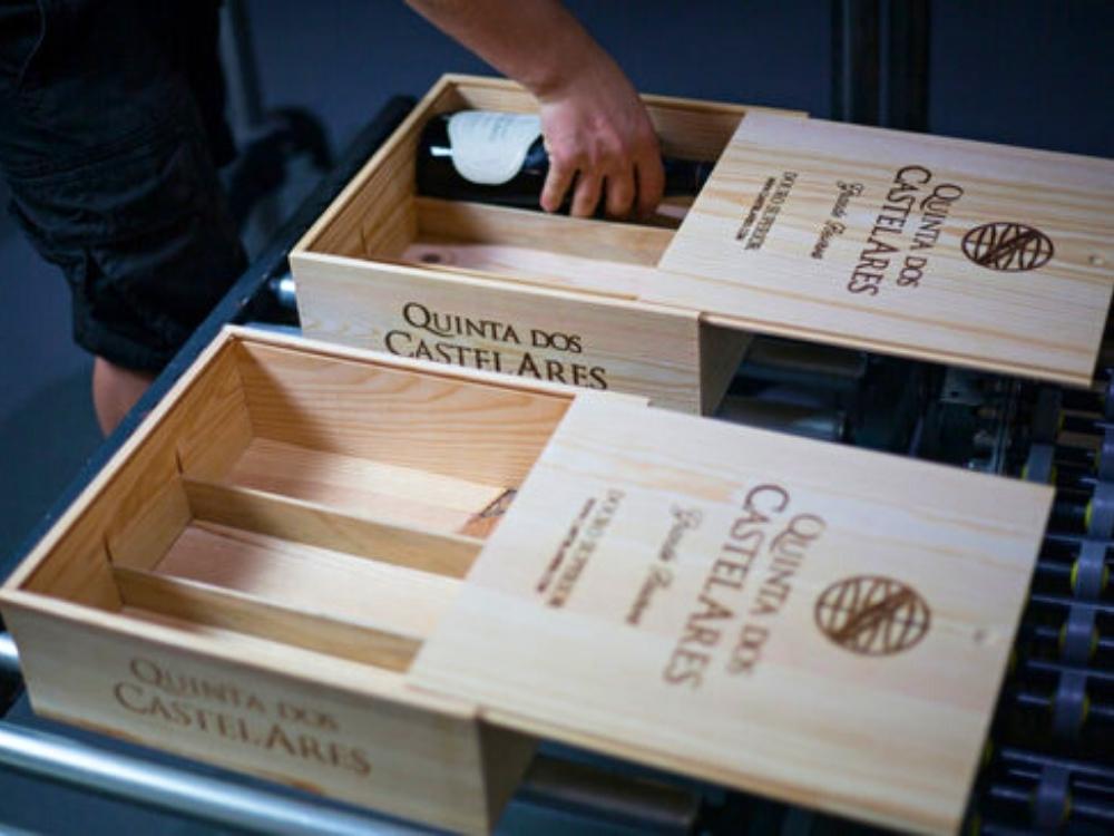 Holzkiste mit Weinen der Quinta dos Castelares, jemand legt eine Weinflasche in die Weinkiste.