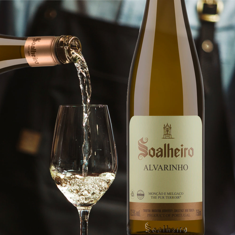Im Bild sieht man einen Barkeeper, der Weißwein in mehrere Weingläser schüttet. Rechts im Bild ist eine Flasche Weißwein Alvarinho vom Weingut Soalheiro in Portugal. Weine erhältlich im Weinversand für Portugal Vinho Bar.