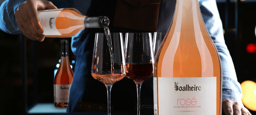 Im Bild sieht man einen Barkeeper, der Roséwein in mehrere Weingläser schüttet. Rechts im Bild ist eine Flasche Roséwein vom Weingut Soalheiro in Portugal. Weine erhältlich im Weinversand für Portugal Vinho Bar.