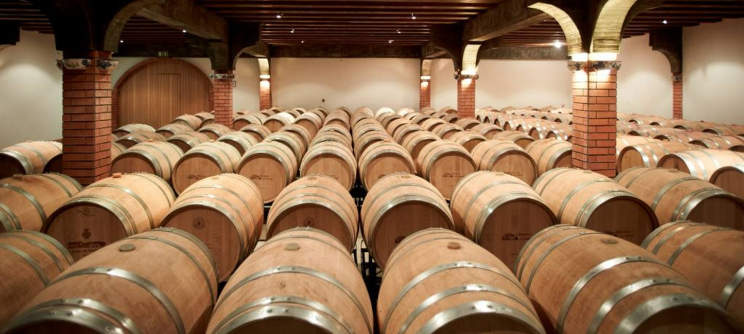 Reihen von Weinfässern aus Eichenholz in einem traditionellen, beleuchteten Barriquekeller des Weinguts Quinta de Cabriz in der Region Dão.