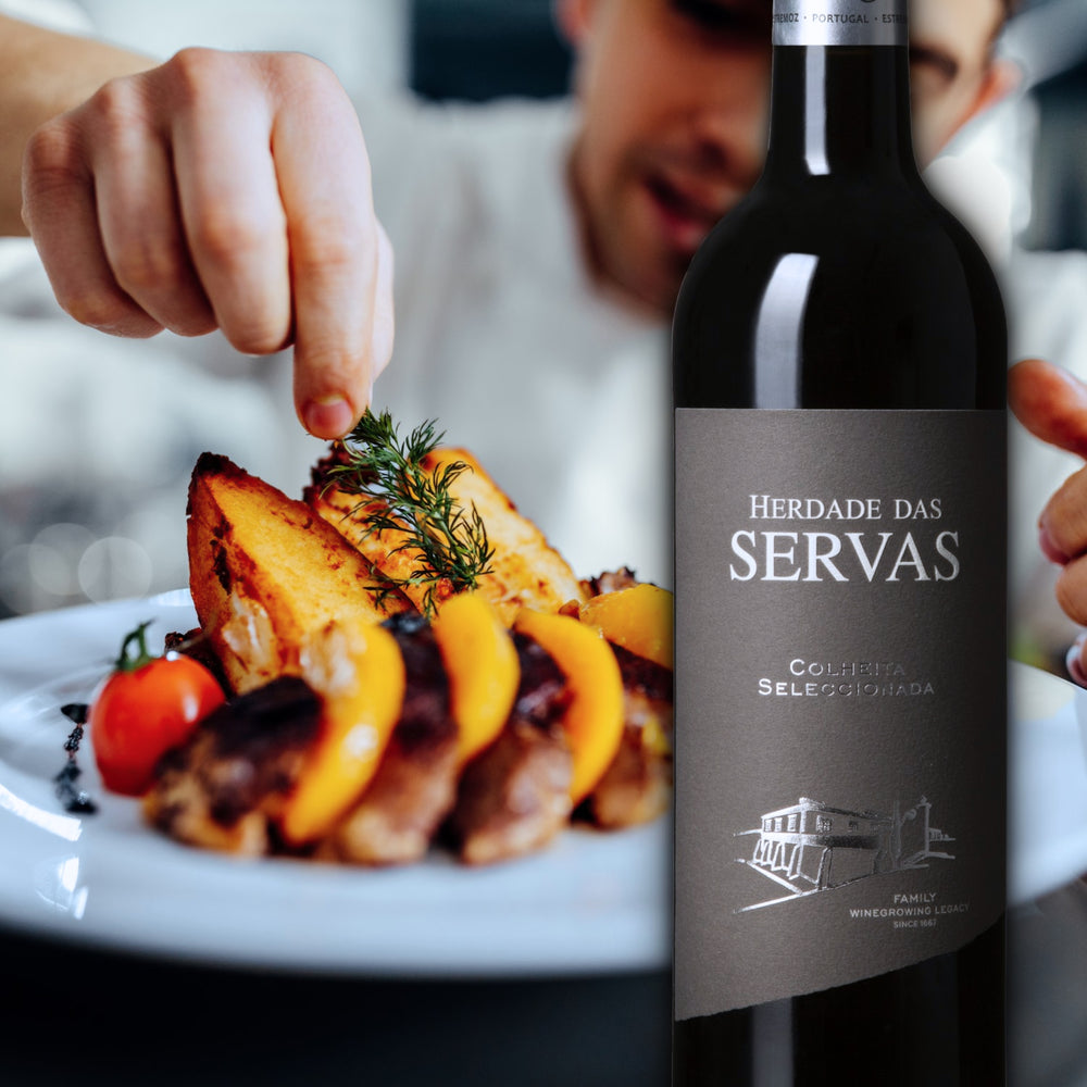 HERDADE DAS SERVAS COLHEITA SELECCIONADA: Rotwein vom Weingut Herdade das Servas aus der Region Estremoz – Alentejo/Portugal. Im Hintergrund ist ein weißer Teller mit Speisen und ein männlicher Koch zu sehen.