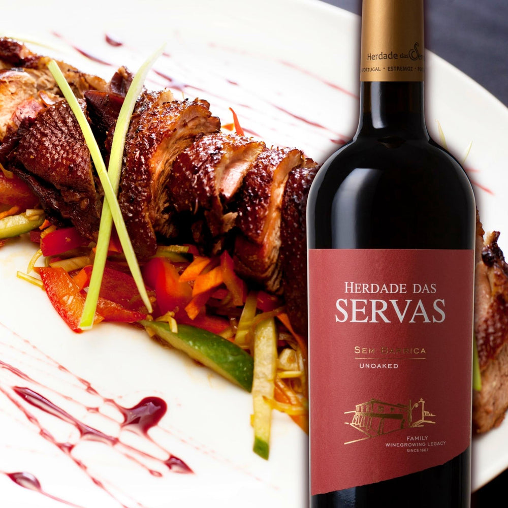 
                  
                    SEM BARRICA - UNOACKED Rotwein vom Weingut Herdade das Servas aus der Region Estremoz – Alentejo/Portugal. Flasche Rotwein mit rotem Etikett vor einem Teller mit gebratener Ente mit knuspriger Haut auf Gemüsebett.
                  
                