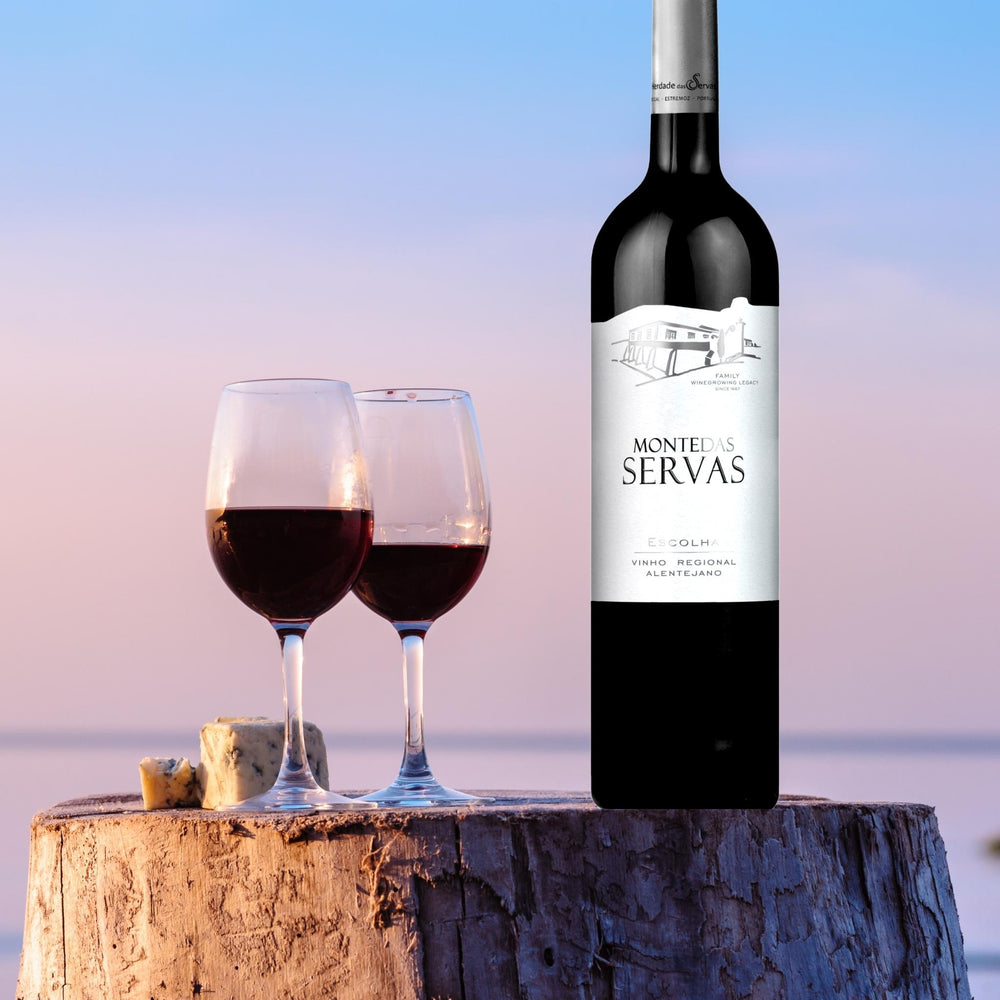 
                  
                    MONTE DAS SERVAS ESCOLHA: Rotwein vom Weingut Herdade das Servas aus der Region Estremoz – Alentejo/Portugal. Weinflasche mit zwei Rotweingläsern auf einem abgesägtem Baumstamm stehend, im Hintergrund etwas Käse. Man sieht eine Landschaft am Meer.
                  
                