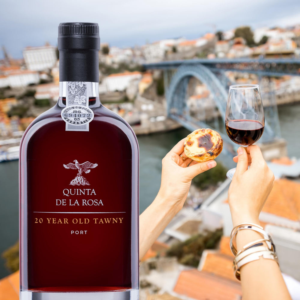 20 YEAR OLD TAWNY PORT vom Weingut Quinta de la Rosa aus Portugal. Bild mit Douro im Hintergrund und Frauenhänden, die ein Portweinglas und ein portugiesisches Puddingtörtchen Pasteis de Nata festhält.