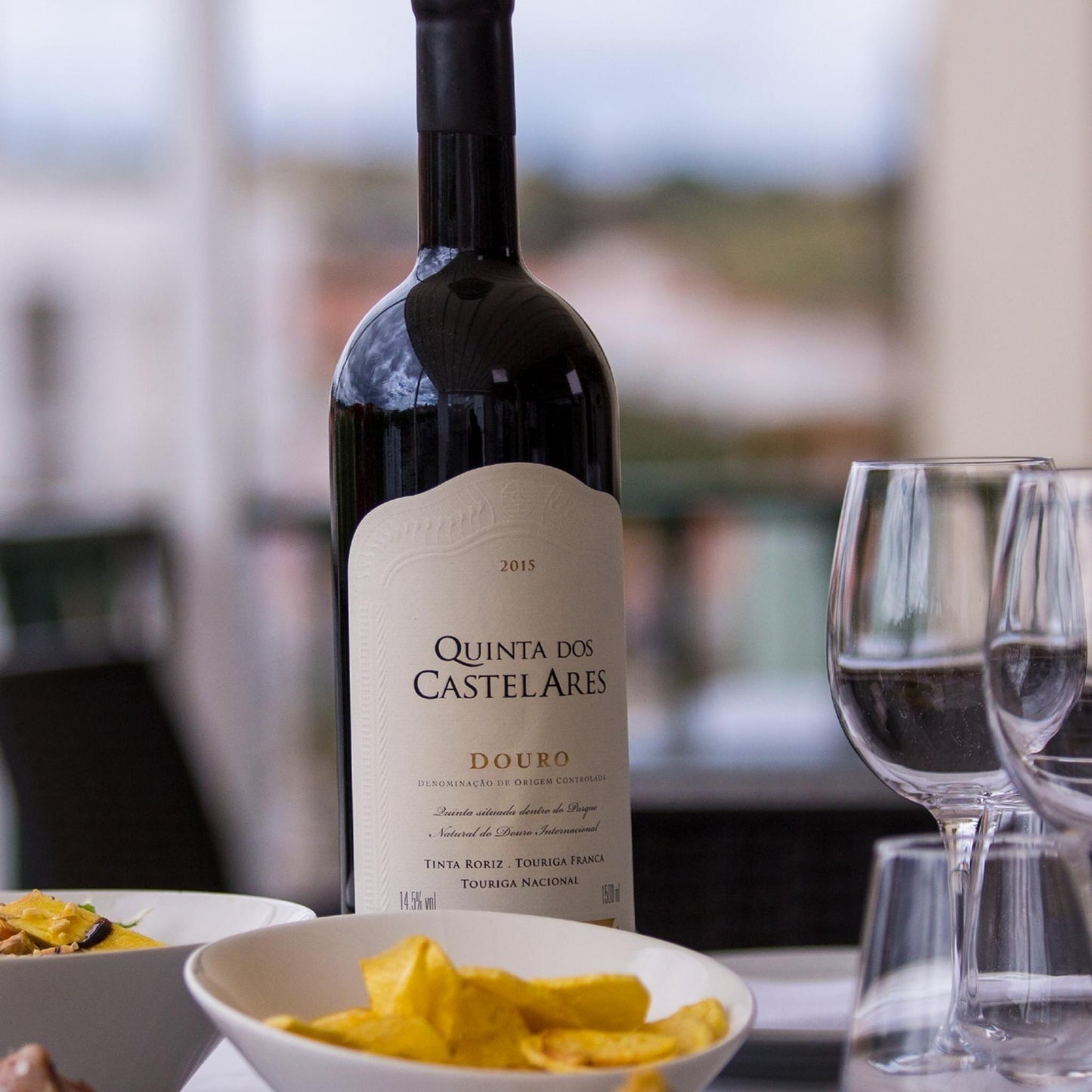 
                  
                    Quinta dos Castelares Reserva, Rotwein aus dem Douro / Portugal. Bild mit Rotweinflasche, leeren Gläsern und Knabbereien auf einem Tisch.
                  
                